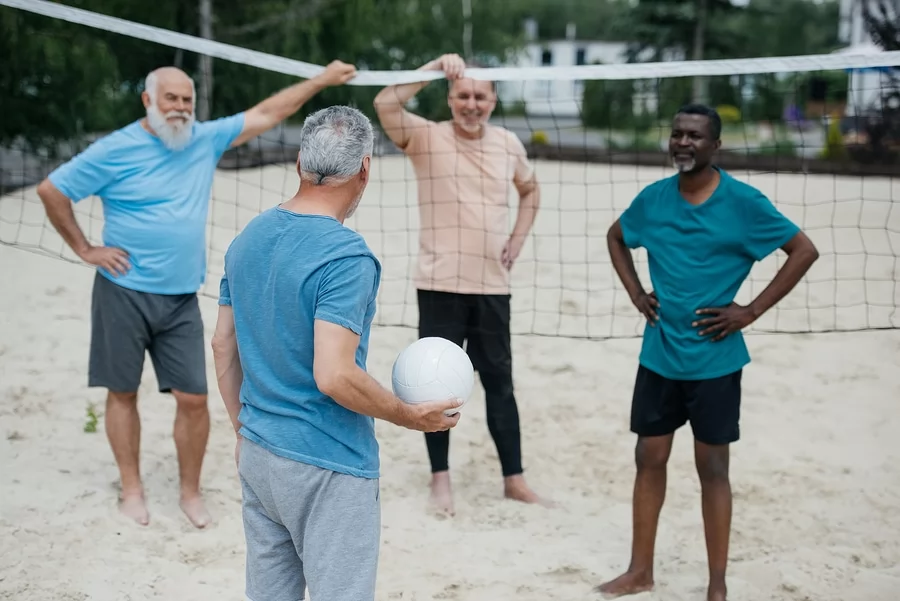 multicultural senior friends playing volleyball games for seniors