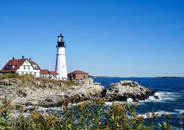 large lighthouse next to shore in Portland, a place to retire in New England
