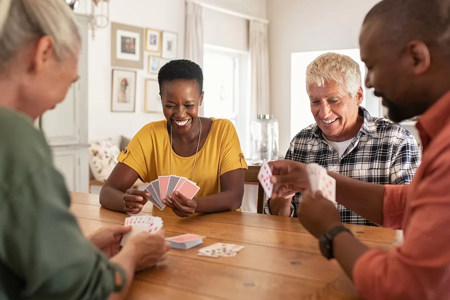Retired multiethnic people playing cards together at home while quarantined