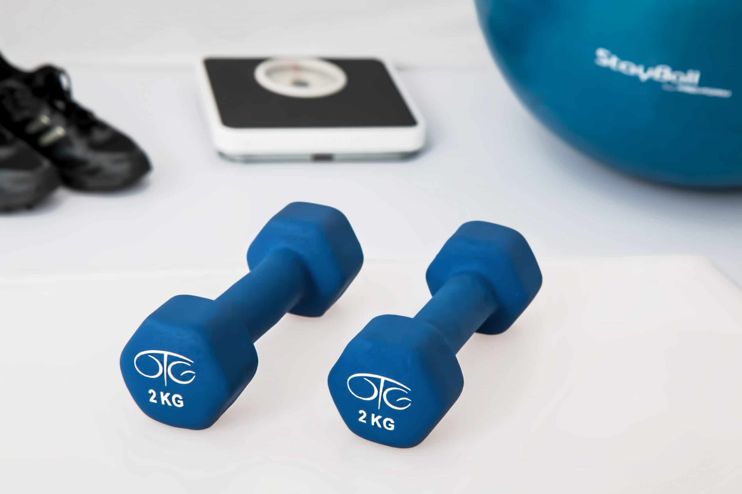 two 2kg blue dumbbells next to various exercise equipment for seniors to stretch