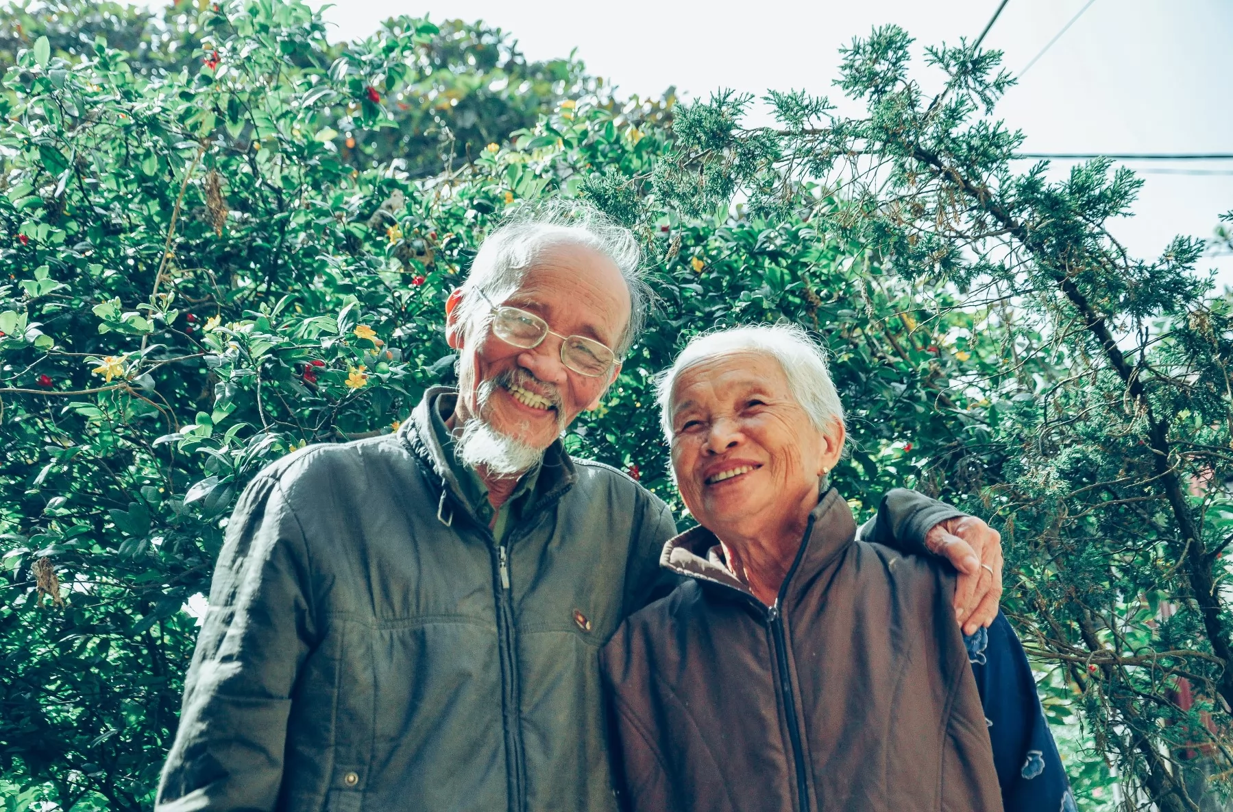 baby boomer embracing and smiling in front of greenery